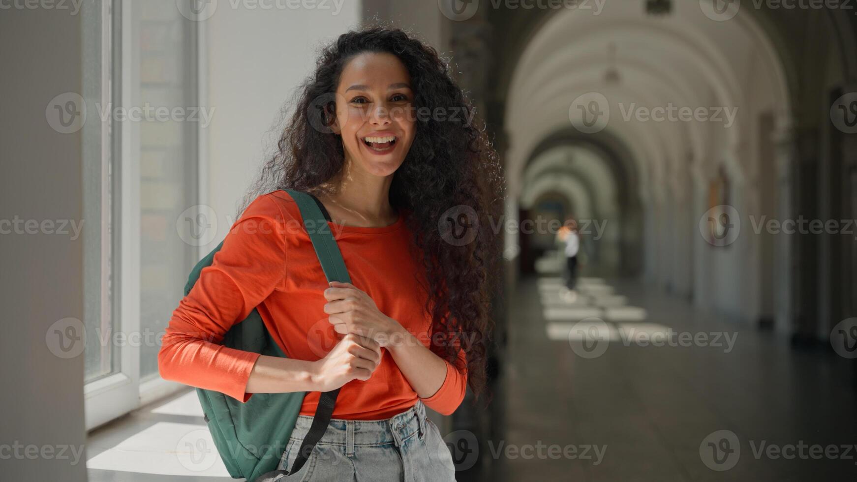 Happy smiling friendly Hispanic woman Latina girl student female in university college academy hall corridor satisfied with education good studying learning pause break looking at camera carefree photo