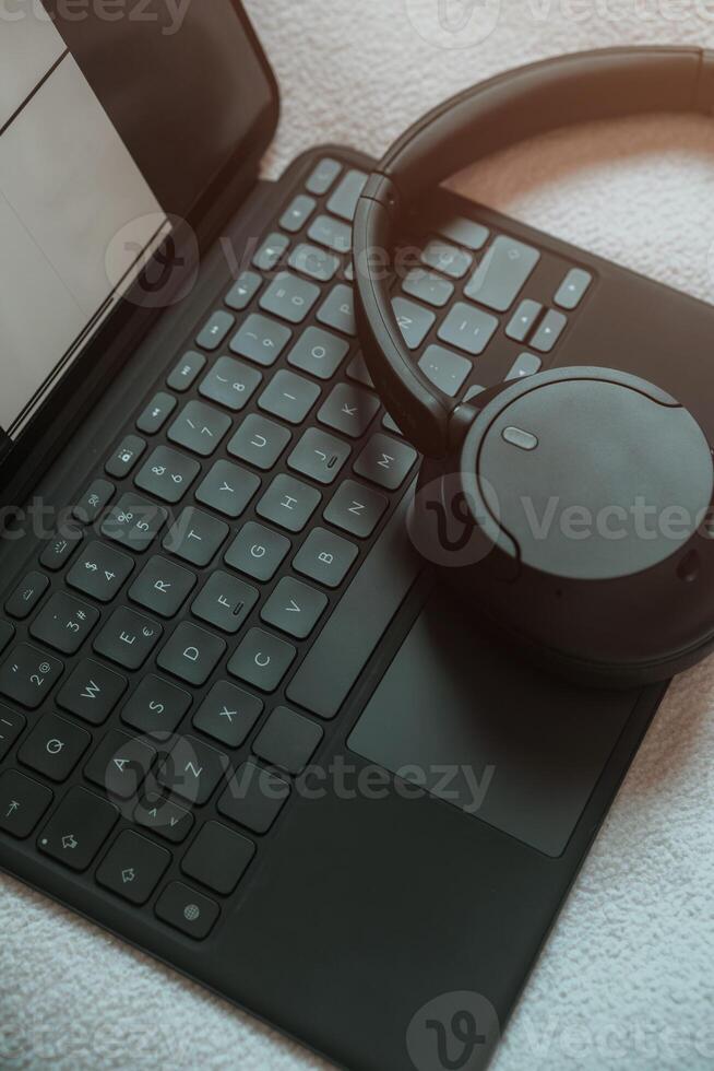 Background image of tablet keyboard and headphones. Moody style workplace and social media concept. photo