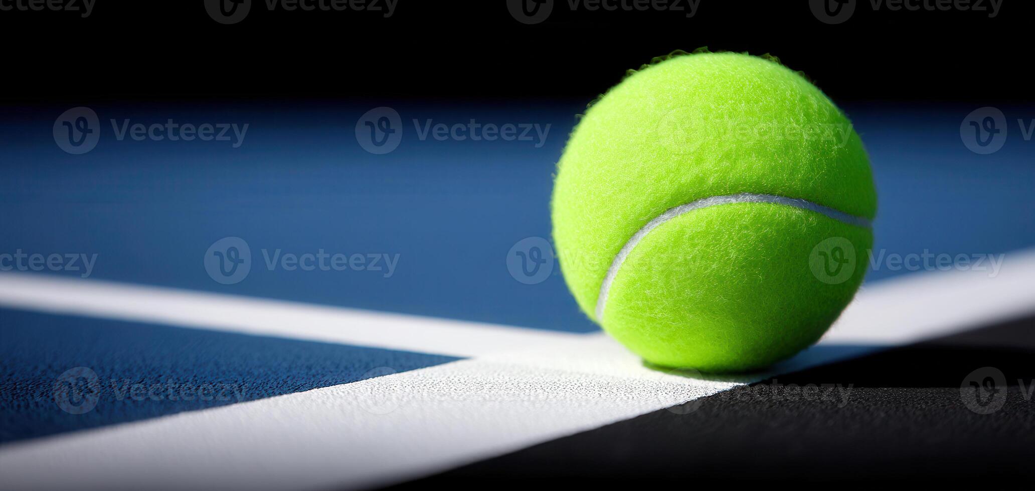Tennis ball resting on white line of blue and black tennis court, showing texture and vibrant color in close up sports scene photo