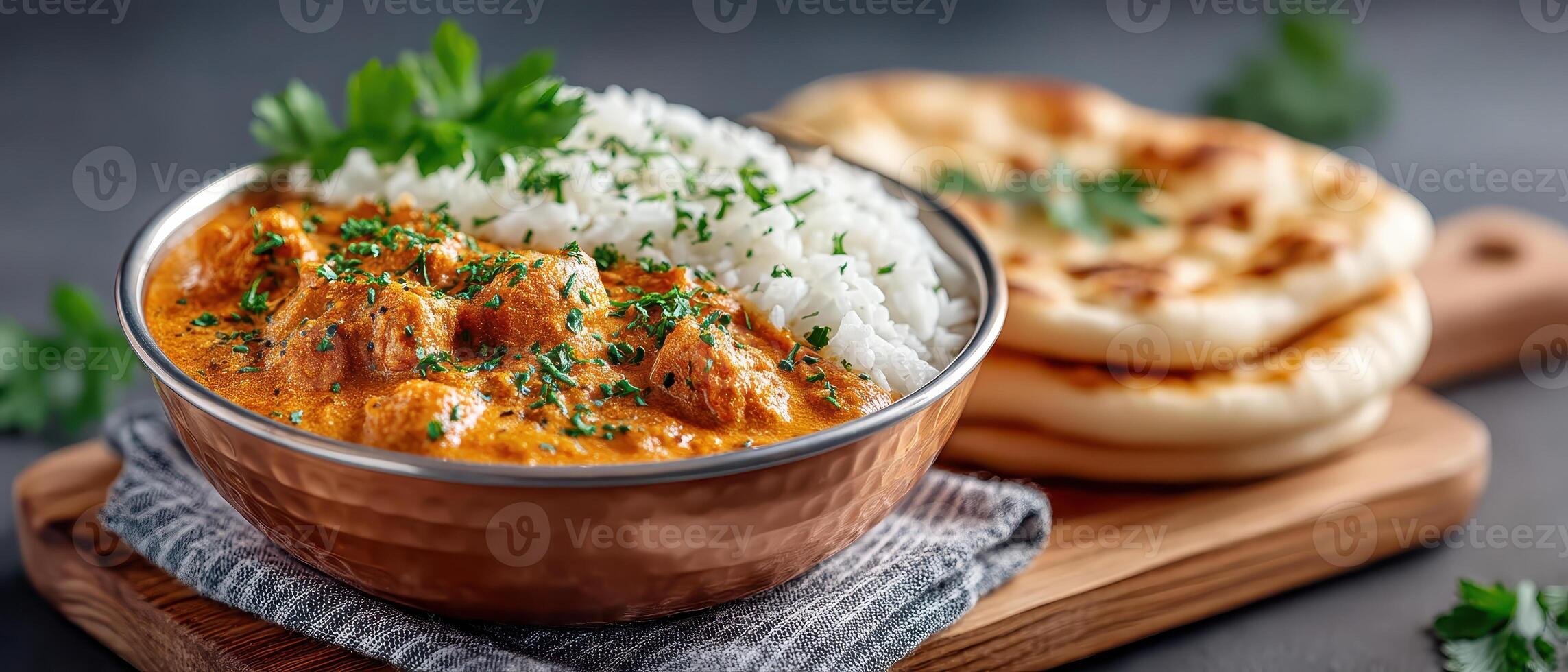 Indian butter chicken served with basmati rice and naan bread on wooden board, garnished with fresh herbs, warm and flavorful meal perfect for dinner photo