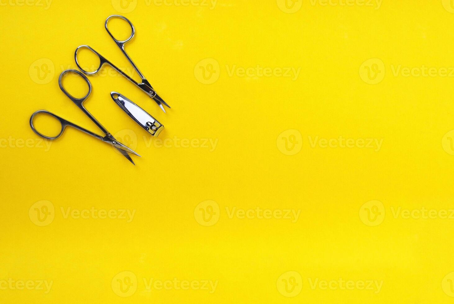 Metal scissors and nippers on a yellow background, space for text. Manicure, pedicure concept. photo