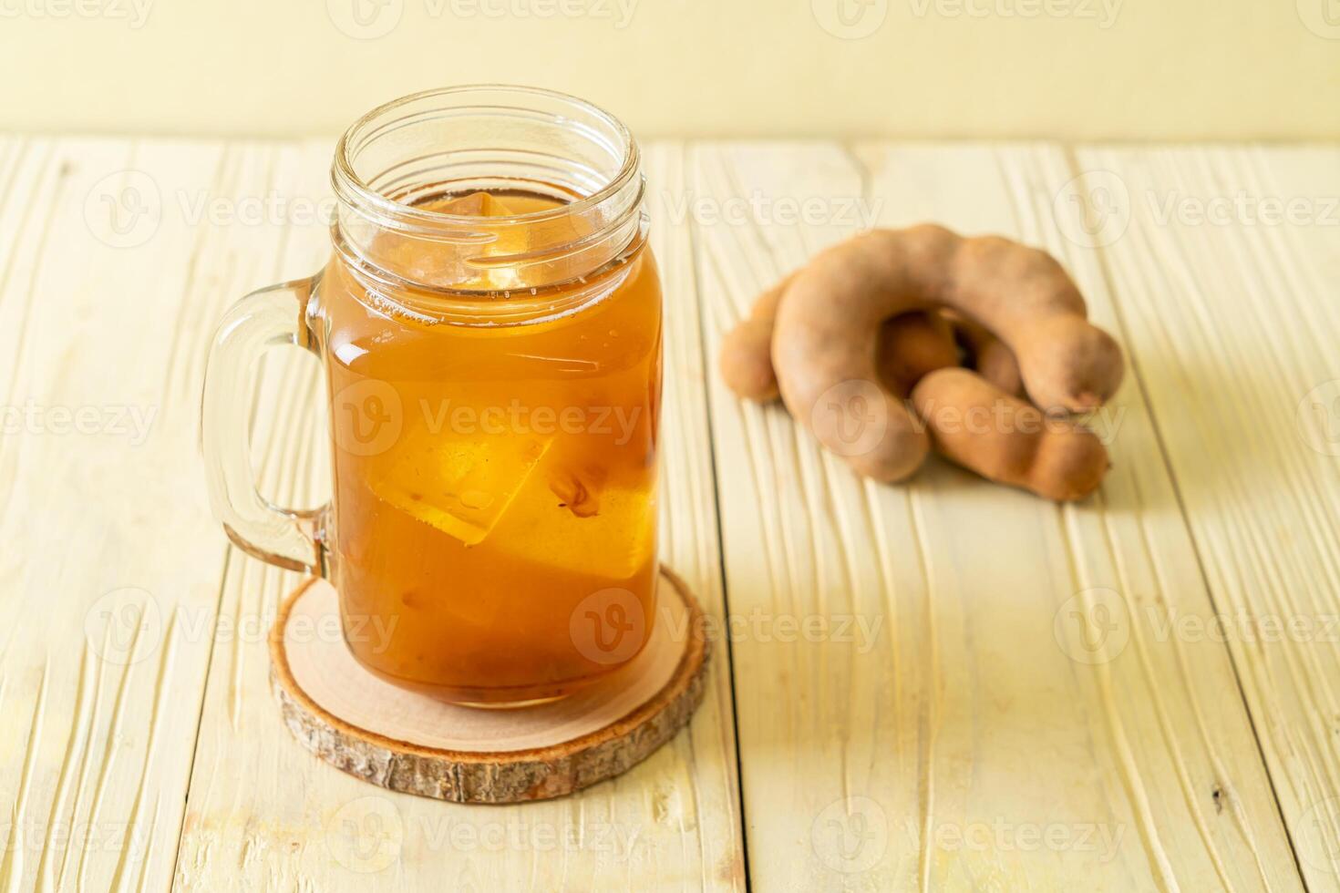Delicious sweet drink tamarind juice and ice cube on wooden backgroud photo