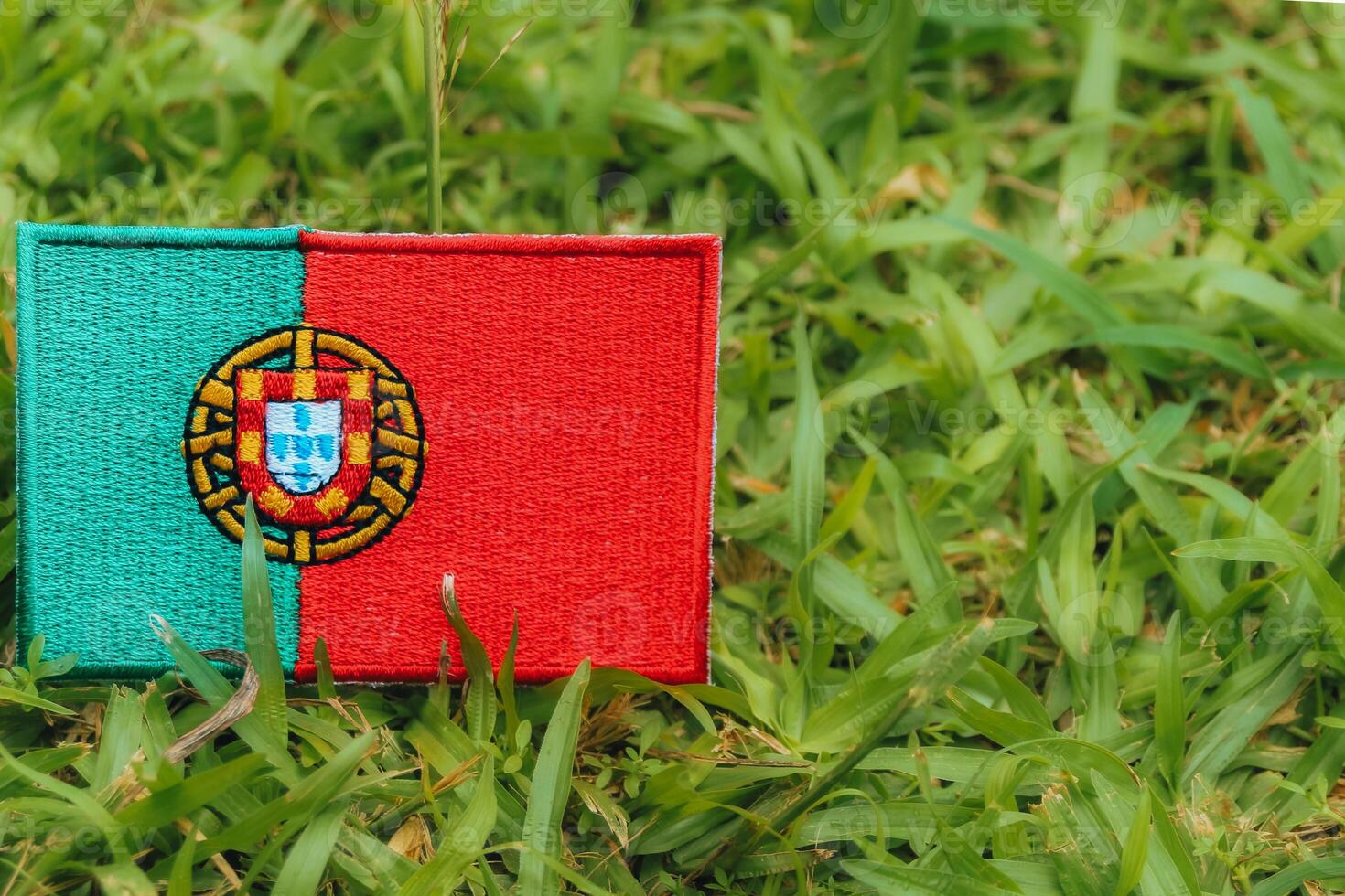 Horizontal eco friendly Portugal flag PT crafted from fabric and thread, placed on green grass in warm natural light. Symbol of climate change, Earth Day and environmental harmony. photo