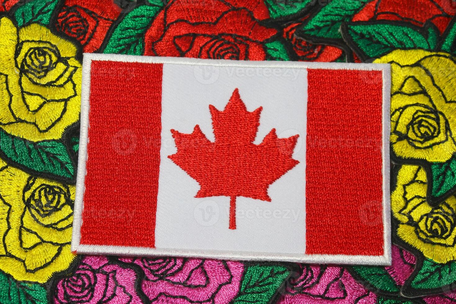 Eco friendly embroidered Canada flag placed on colorful handmade floral embroidery of roses, crafted from thread and fabric. Cultural and natural harmony. photo