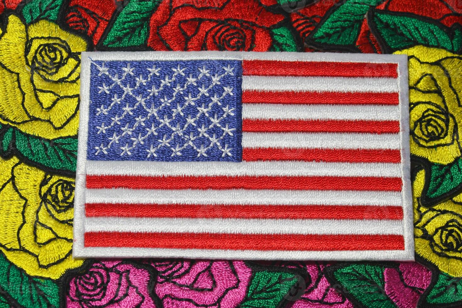 Eco friendly embroidered USA flag placed on colorful handmade floral embroidery of roses, crafted from thread and fabric. Symbol of American pride and craft. photo