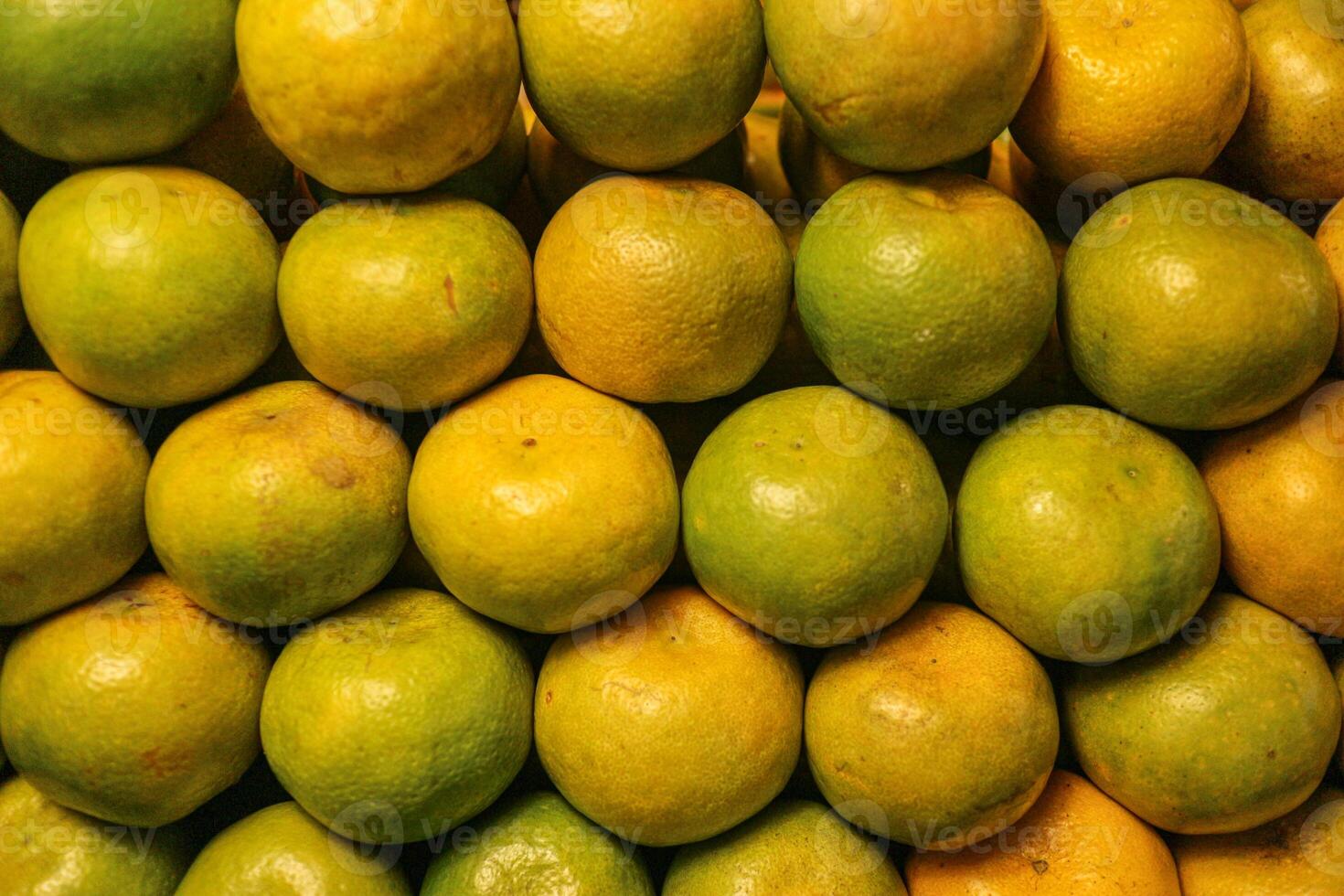 Horizontal wide angle view of fresh Thai honey tangerines with golden yellow and green peel, sweet tangy taste and textured skin, arranged as local street food. photo
