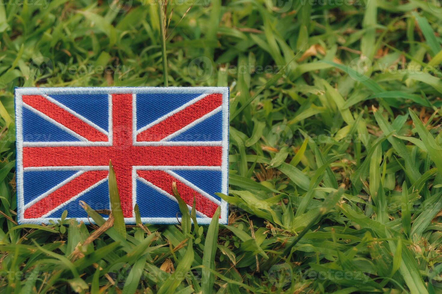 Horizontal eco friendly Union Jack flag, made from fabric and thread, placed on green grass under warm light in Europe. Symbolizing climate change, Earth Day and environmental harmony. photo