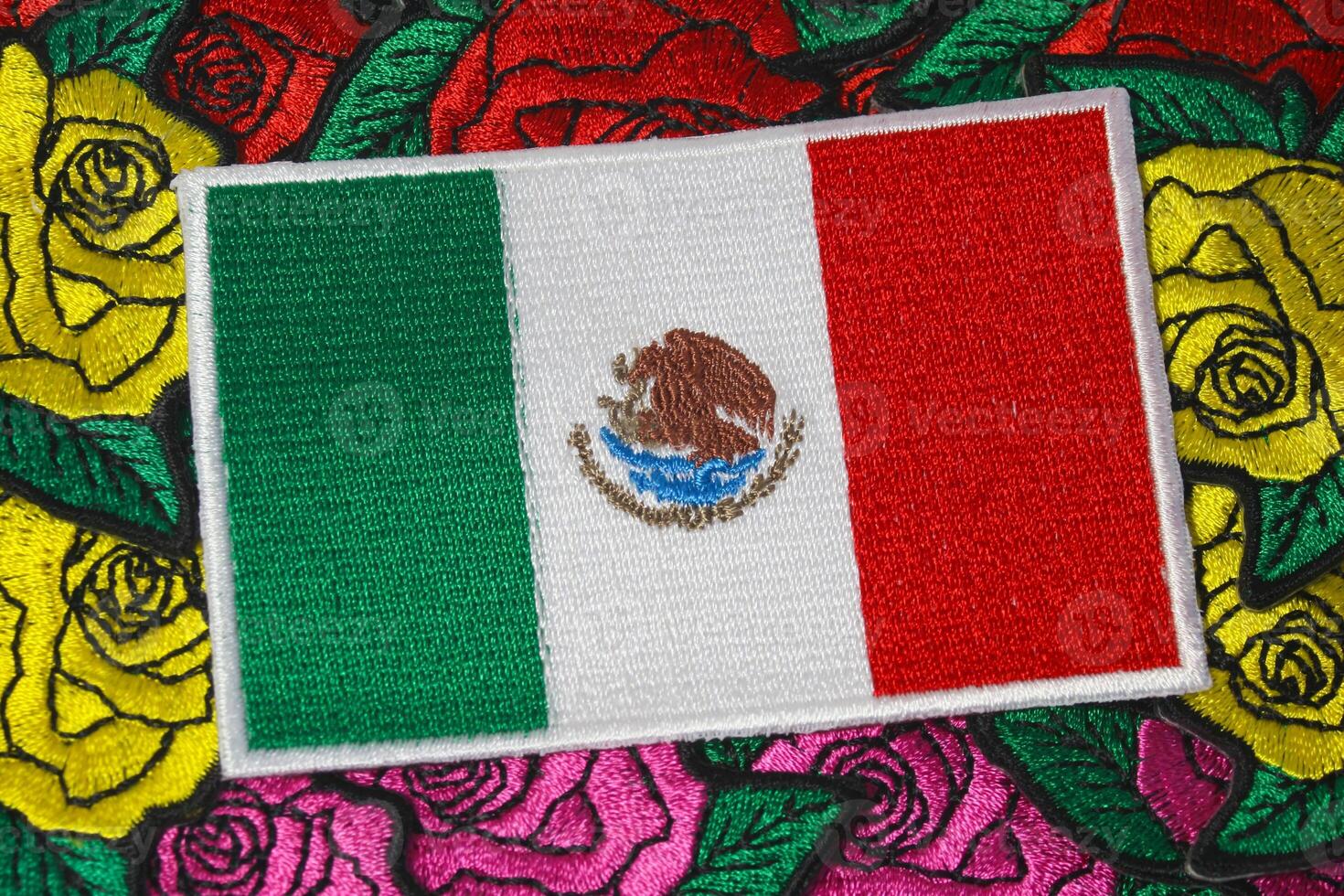 Eco friendly embroidered Mexican flag placed on vibrant handmade floral embroidery of roses. Crafted with colorful threads, symbolizing culture and sustainability. photo