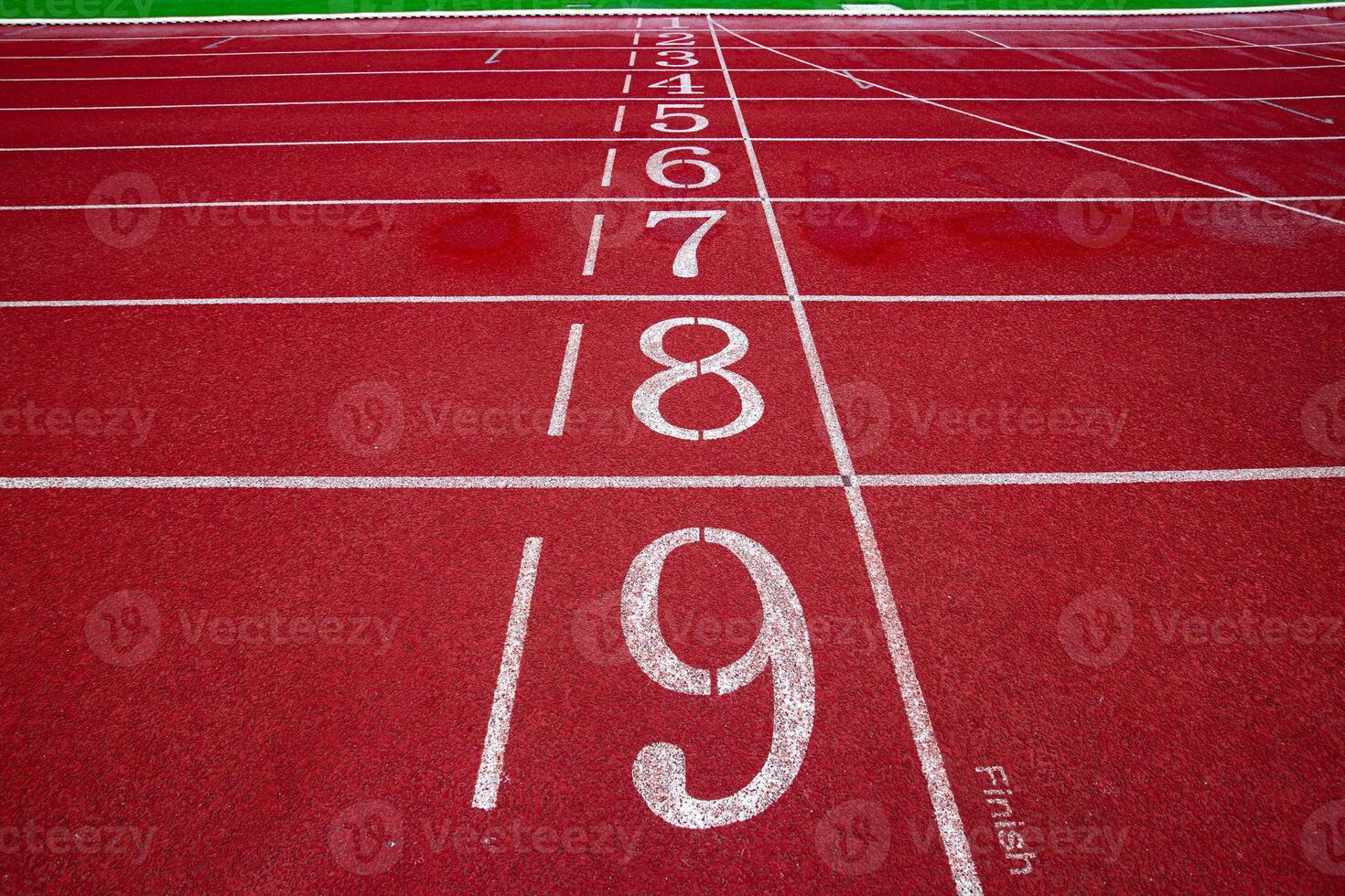 Horizontal wide shot of running track finish line, lanes 1 to 9 red surface and white stripe, symbolizing competition, motivation and victory. photo