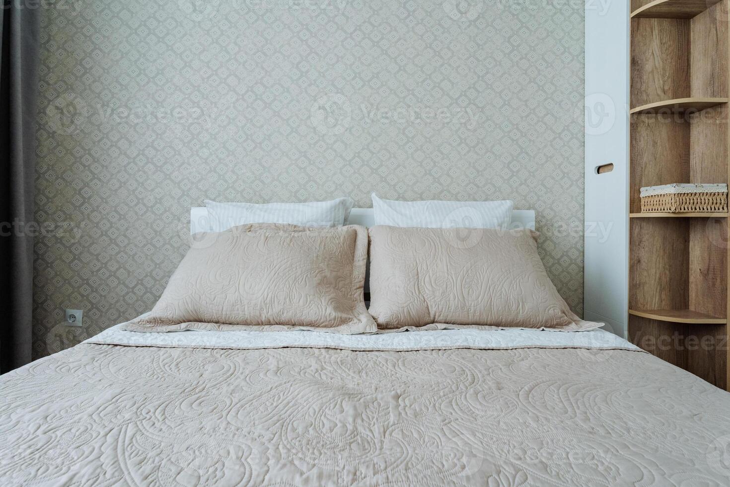 In a cozy bedroom, there sits a bed adorned with a warm blanket and several plush pillows, positioned adjacent to an inviting bookshelf filled with various books and decorative items photo