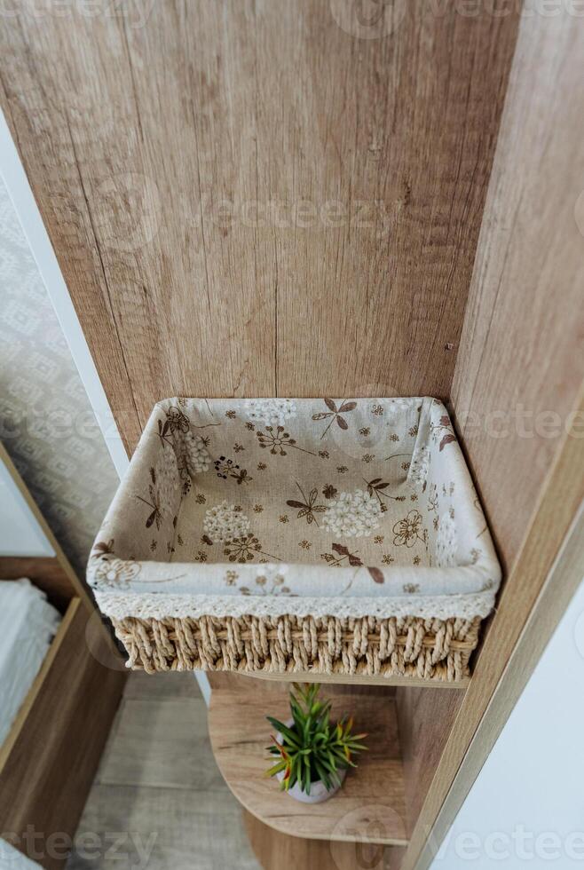 A beautiful basket is sitting prominently on a sturdy wooden shelf right next to a vibrant green plant, creating a lovely natural decor that enhances the surrounding space photo