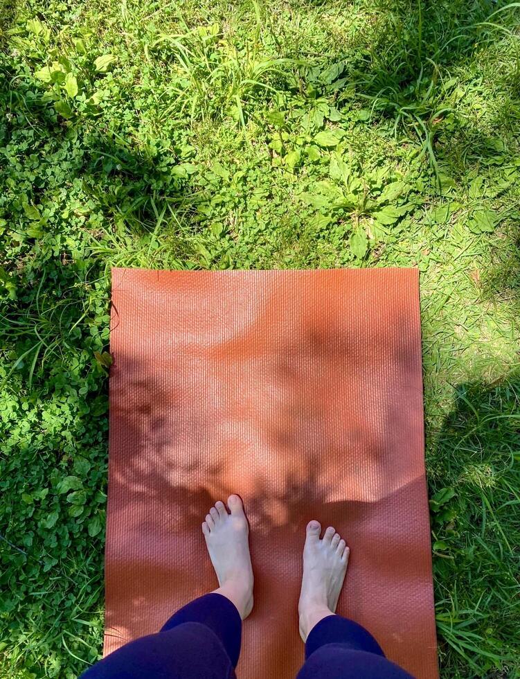 A person standing on a yoga mat in the grass photo