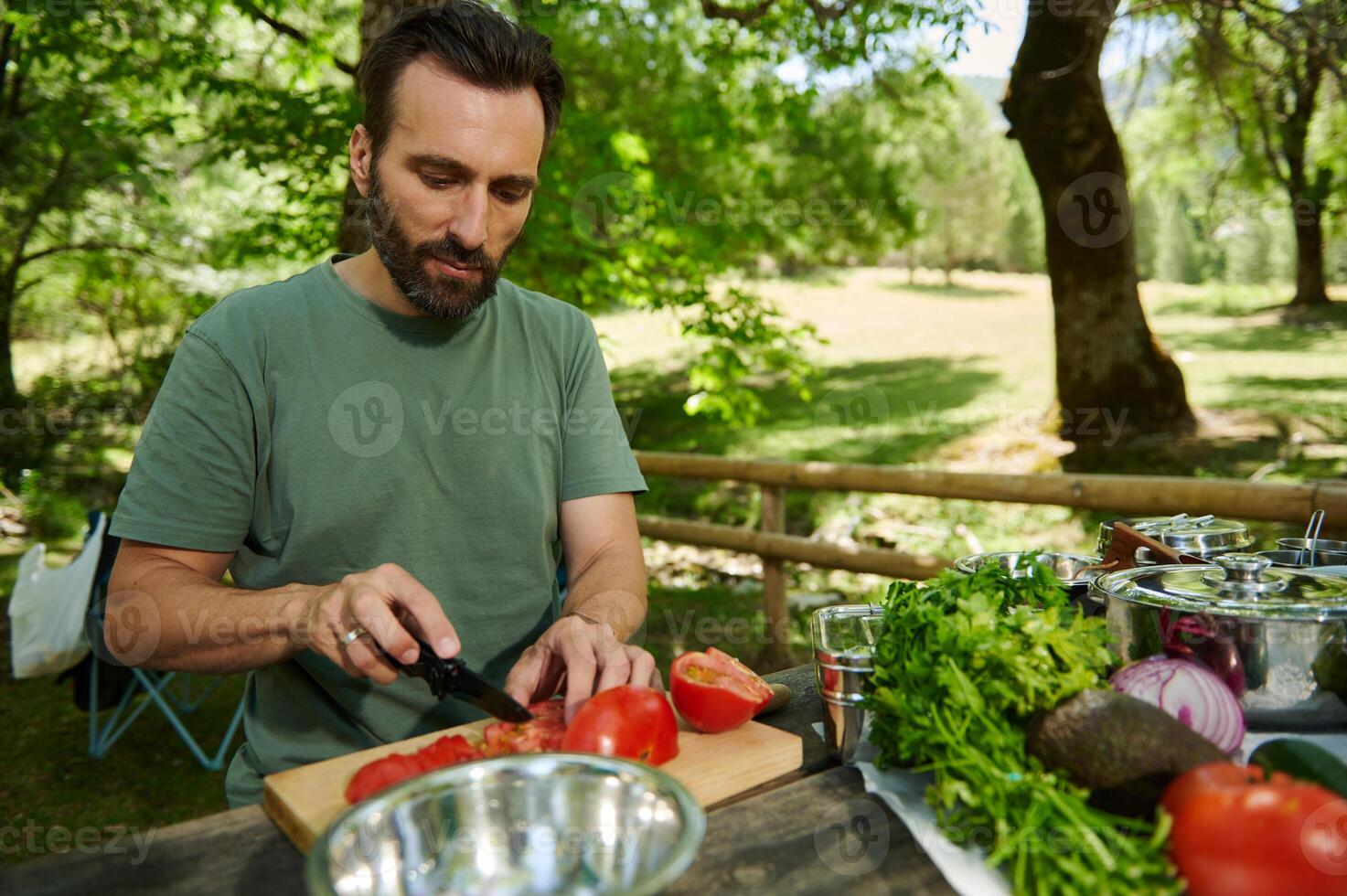 Man Preparing Fresh Ingredients Outdoors at a Camping Picnic on a Sunny Day photo
