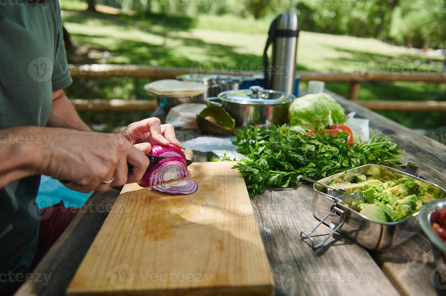 Person Preparing Vegetables on Wooden Cutting Board Outdoors for a Picnic Meal photo