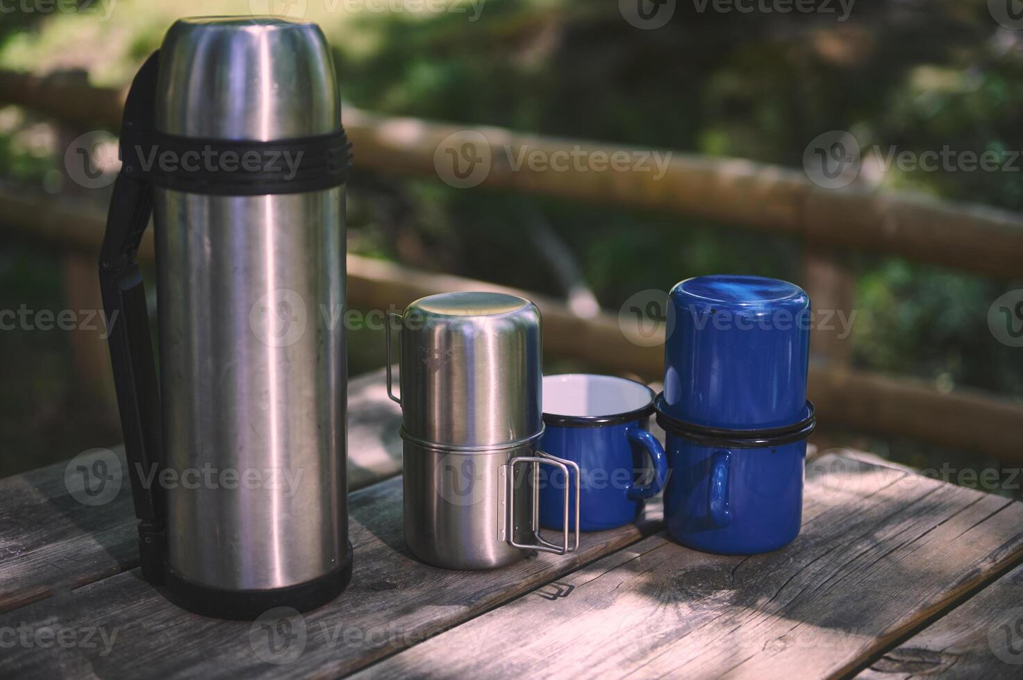 Outdoor Picnic Setup with a Thermos and Mugs on Wooden Table photo