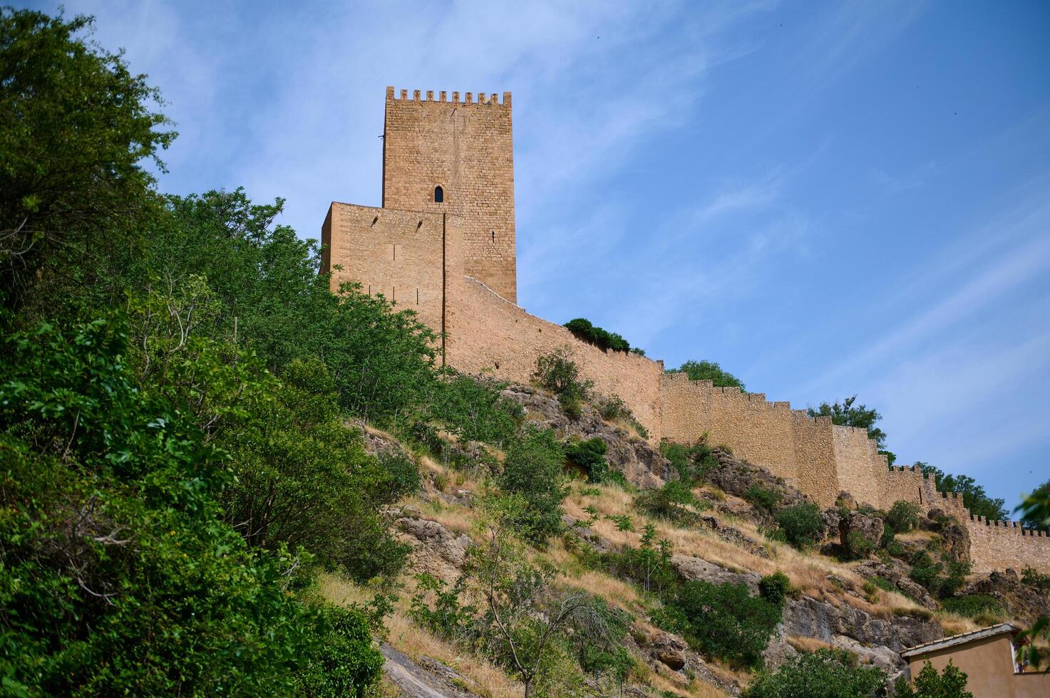 Beautiful Medieval Stone Tower Surrounded by Lush Greenery Under a Vibrant Blue Sky photo