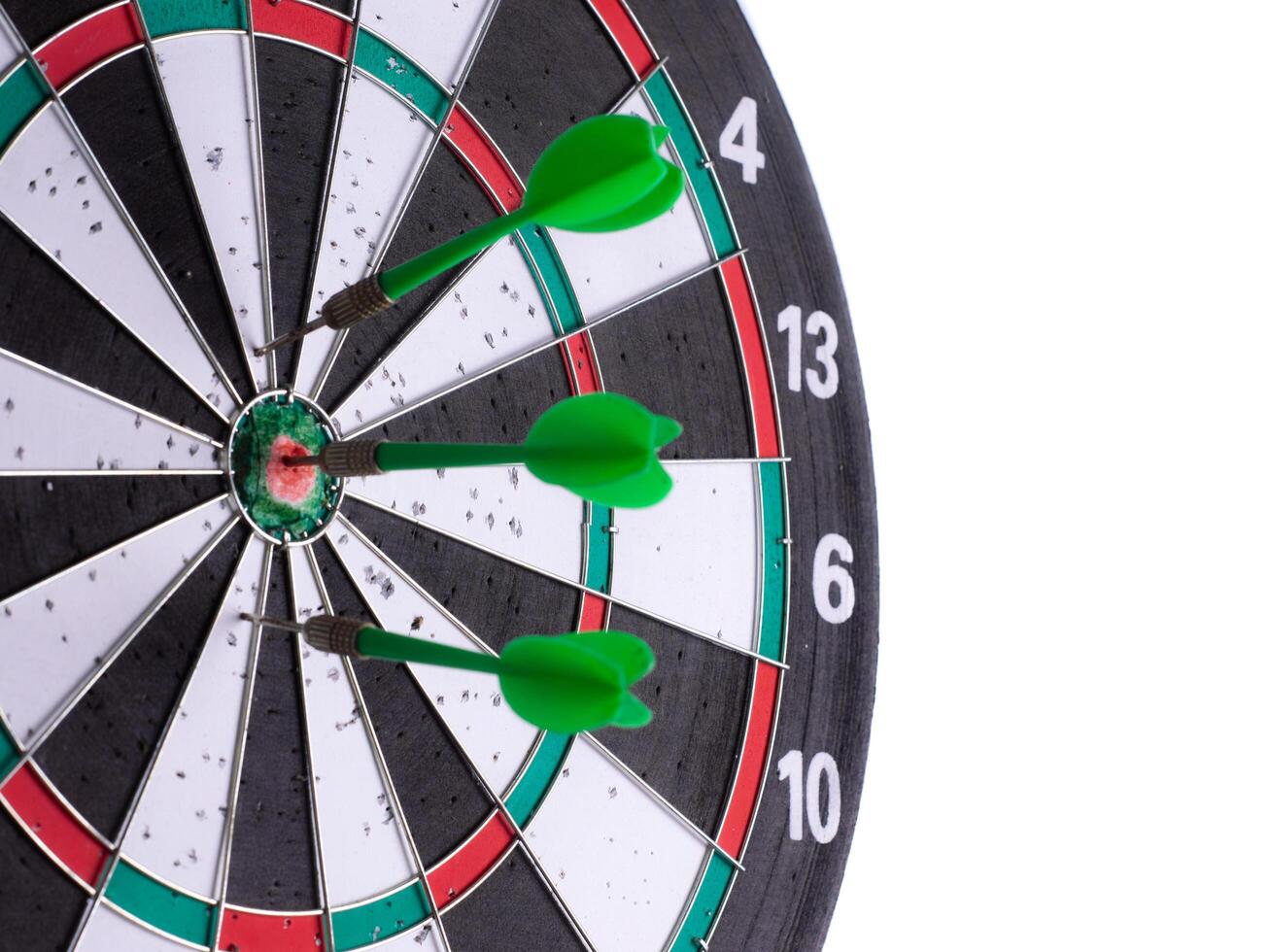 Side view of close up green darts hitting target on dartboard isolated on white background. Business success, precision, accuracy, focus, strategic planning, leadership, marketing concept. photo