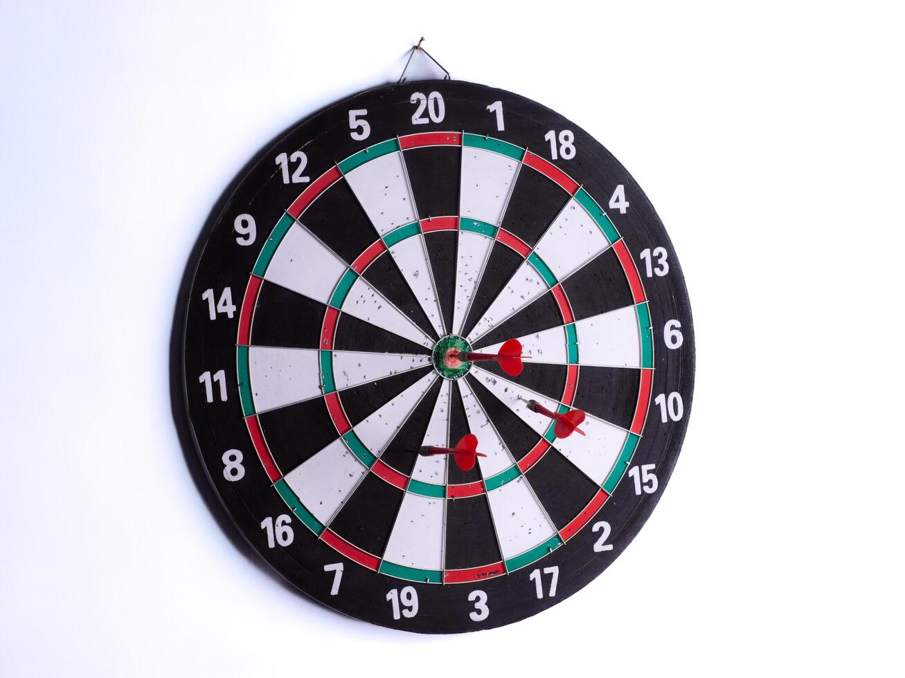 Three red dart hitting bullseye on dartboard isolated on white background. Perfect target accuracy, success, focus, business strategy, goal achievement, competition and leadership concept. photo