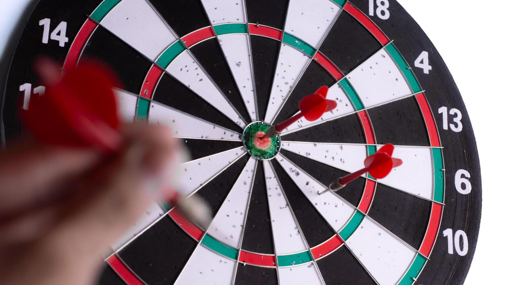 Close up hand holding red dart aiming at dartboard target. Business strategy, focus, precision, planning, leadership and success concept isolated on white background. photo