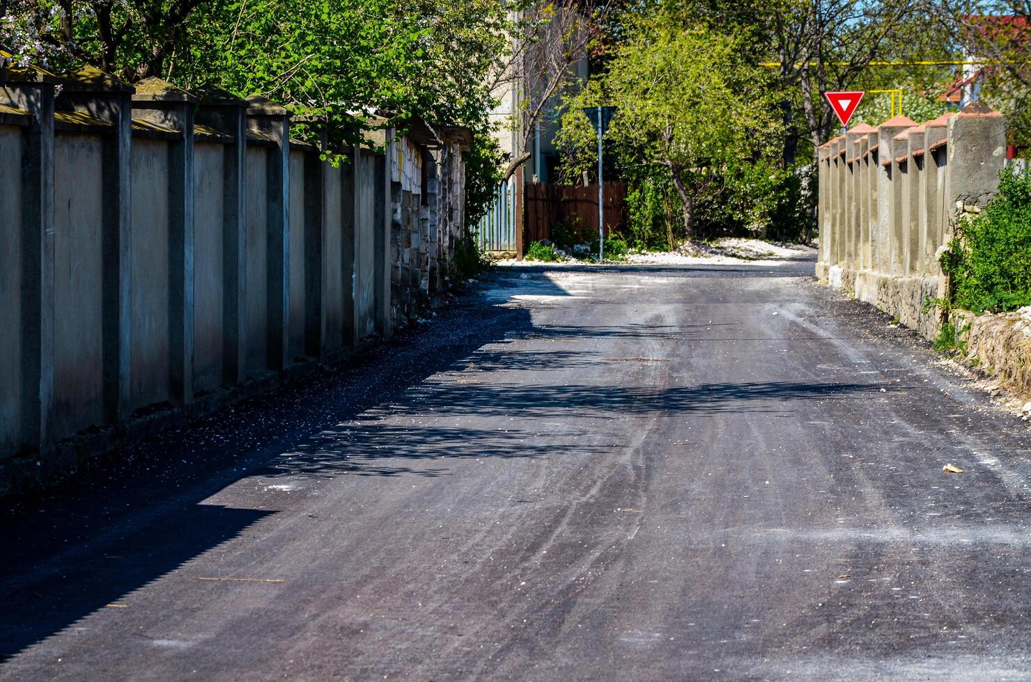 A road with a white sign that says yield on it. The road is empty and there are no cars or people on it photo