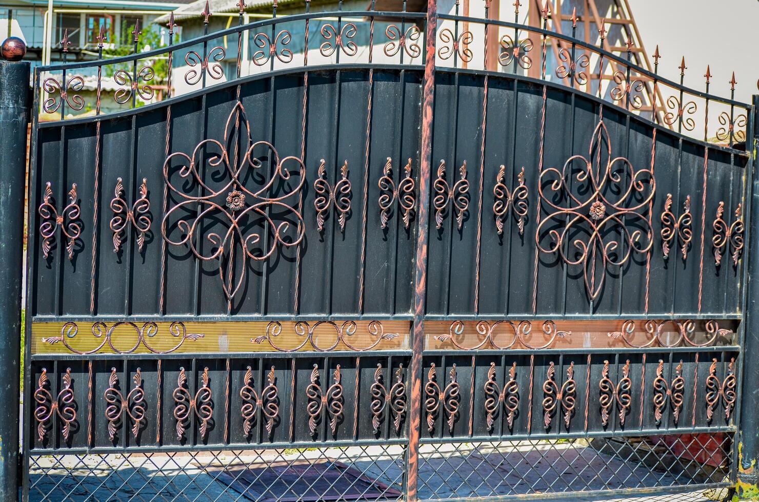 A wrought iron gate with a gold and black design. The gate is ornate and has a lot of detail photo
