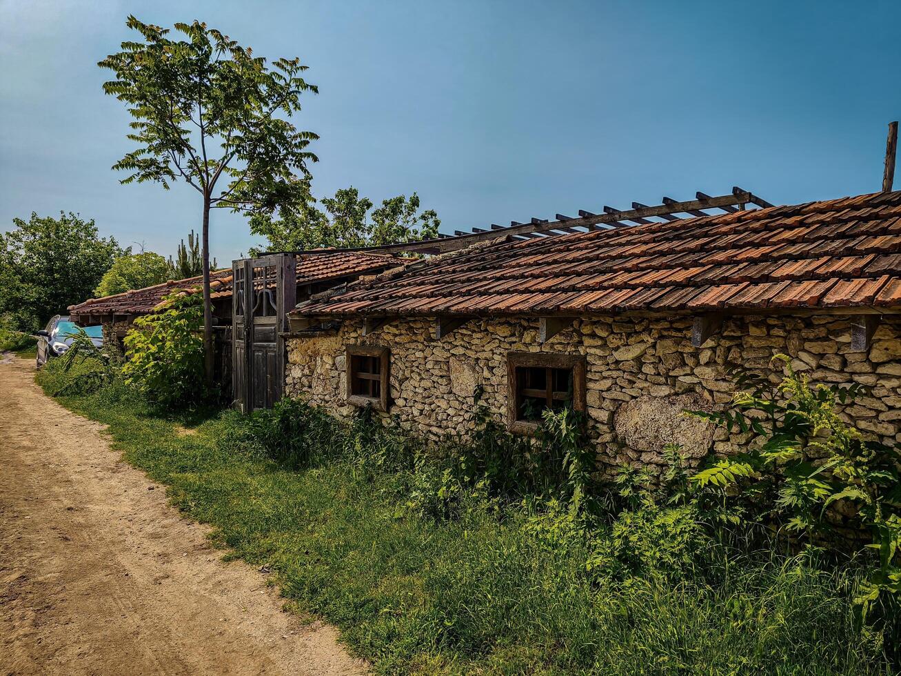 A small house with a red roof and a gate. The gate is open. The house is surrounded by a lot of grass photo