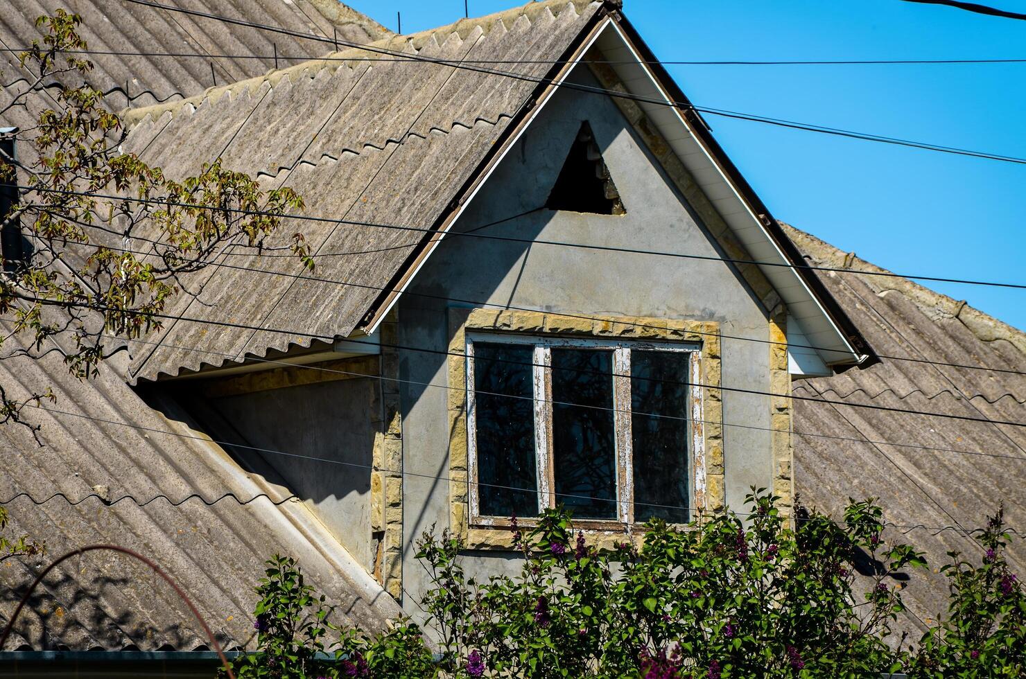 A house with a slanted roof and a window. The roof is made of shingles and the window is open photo