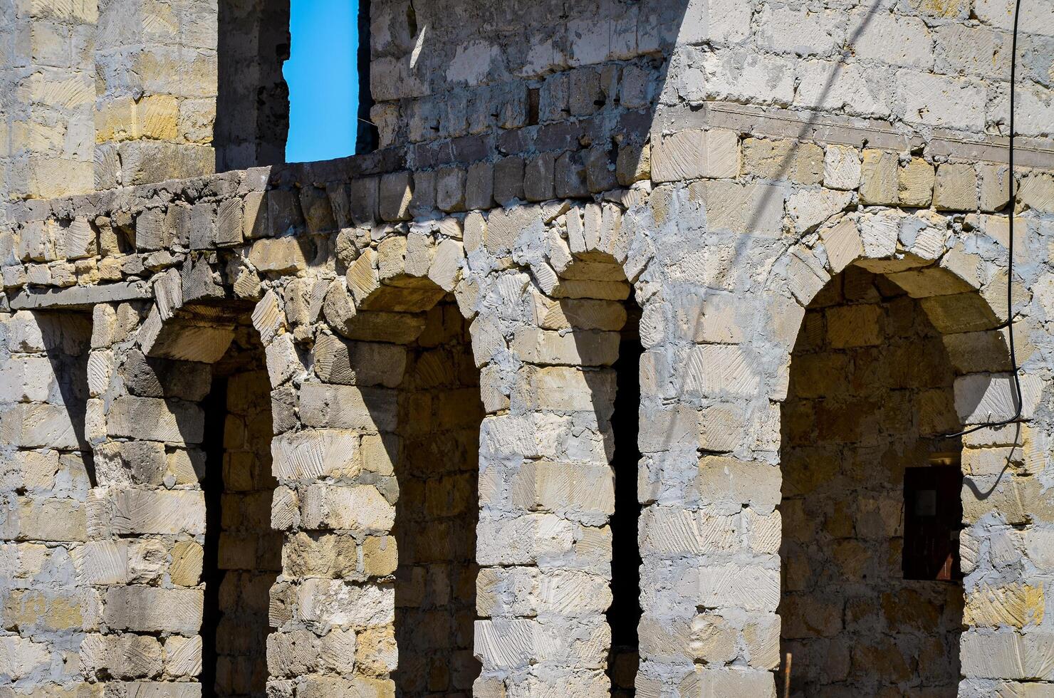 The entrance to the building is made of stone and has an arched design. The stone is grey and the arch is quite large, giving the entrance a sense of grandeur photo
