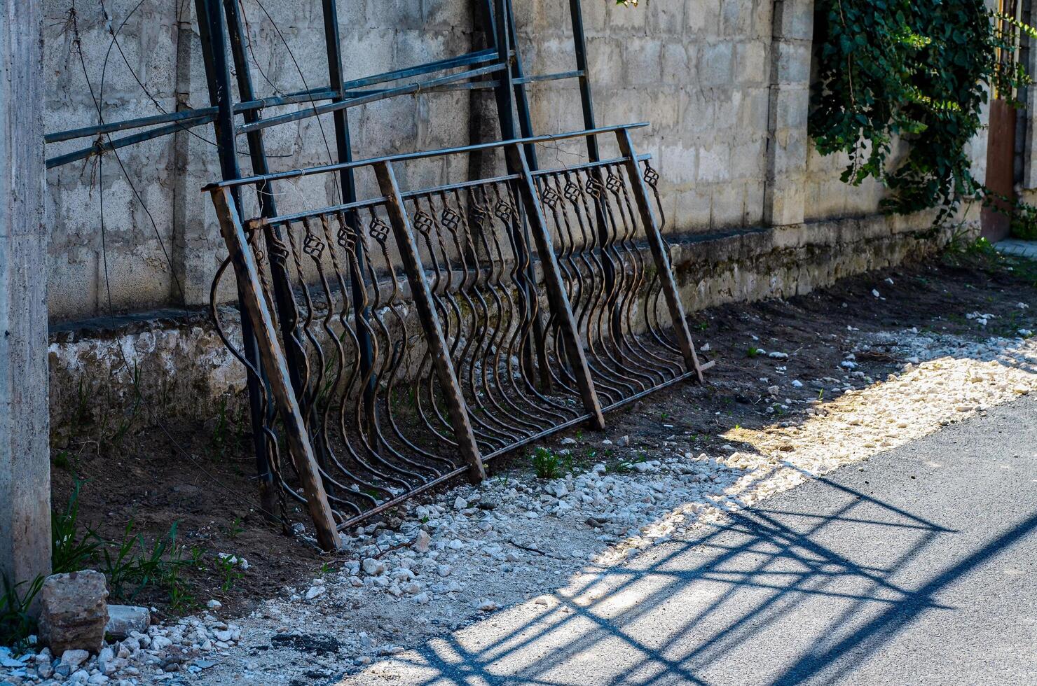 A fence is leaning against a wall. The fence is made of metal and has a lot of detail photo