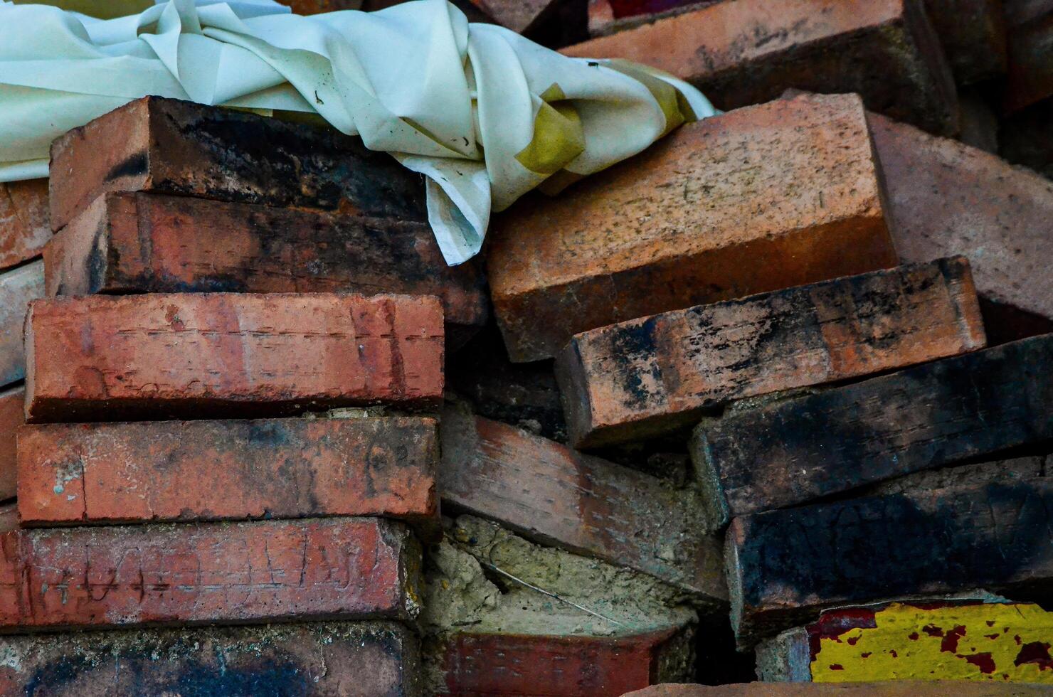 A pile of bricks with a white cloth on top. The bricks are old and worn, and the cloth is torn. Scene is one of decay and abandonment photo
