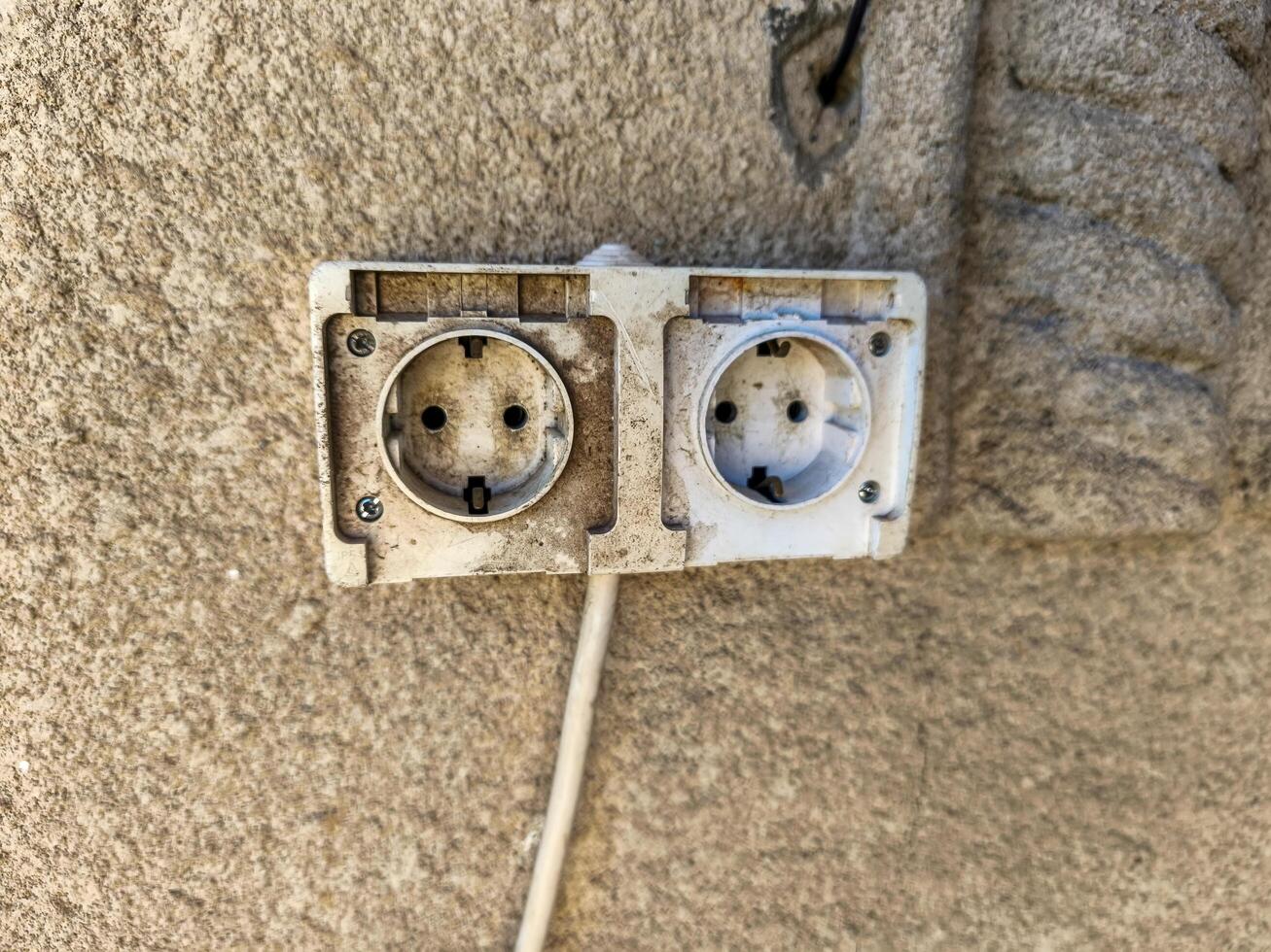 Two white outlets on a wall. The outlets are dirty and have a lot of dirt on them photo