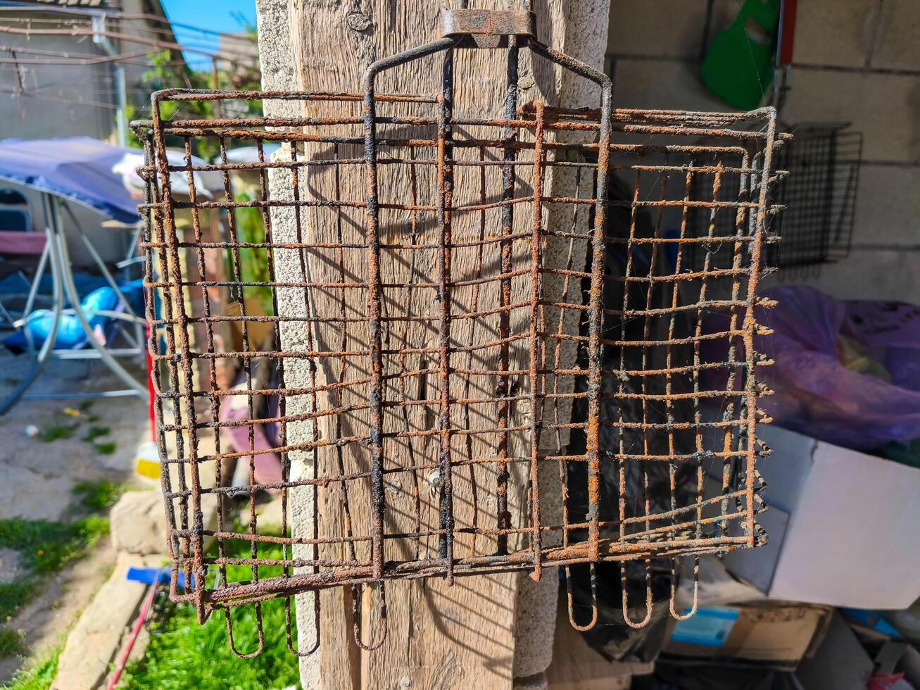 A rusty metal cage with a black and white pattern. The cage is hanging on a wall. The cage is old and has a lot of rust on it photo