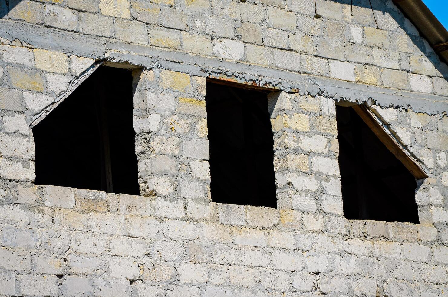 A building with three windows and a roof. The windows are open and the building is empty. Scene is somewhat lonely and abandoned photo