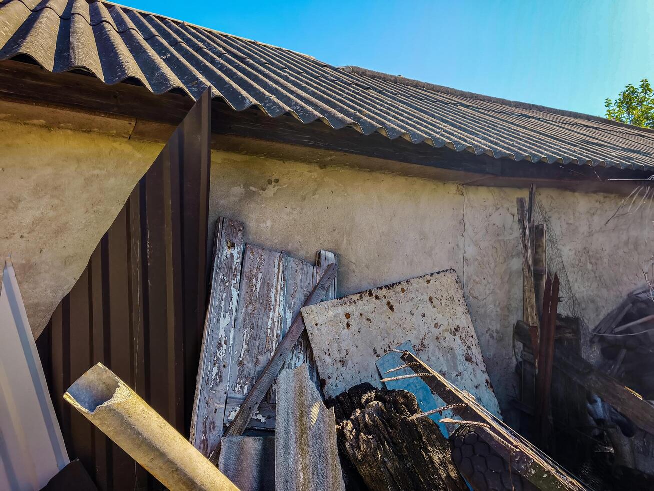 A pile of debris and junk is on the ground, with a roof above it. Scene is chaotic and disorganized photo