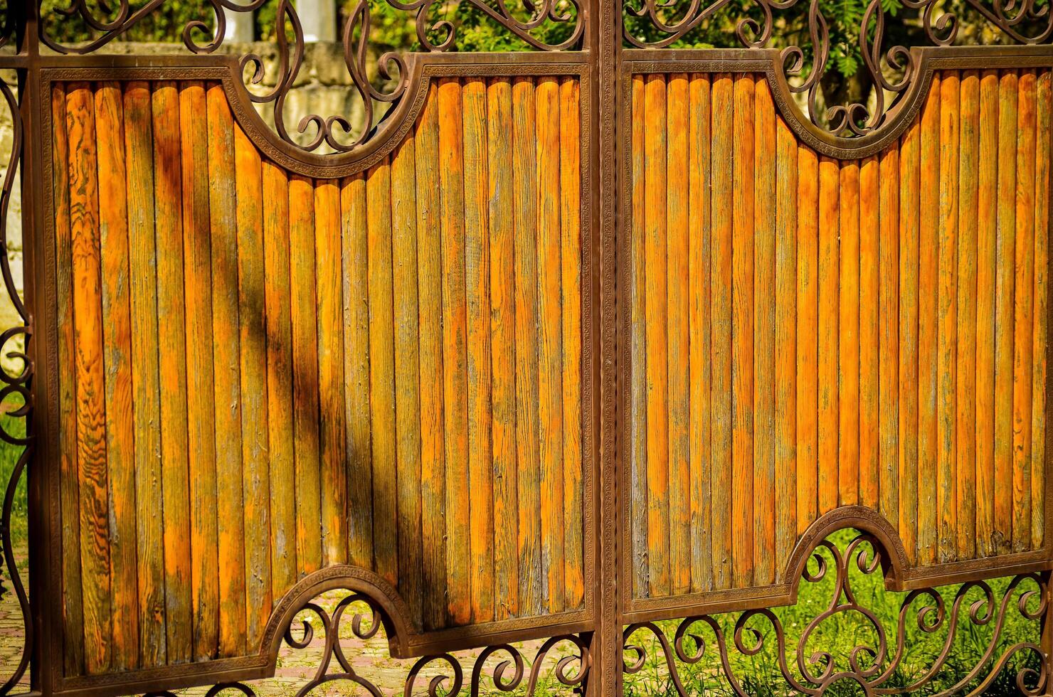 The fence is made of wood and has a rustic look. The wood is weathered and has a brownish hue. The fence is surrounded by a green grassy area photo