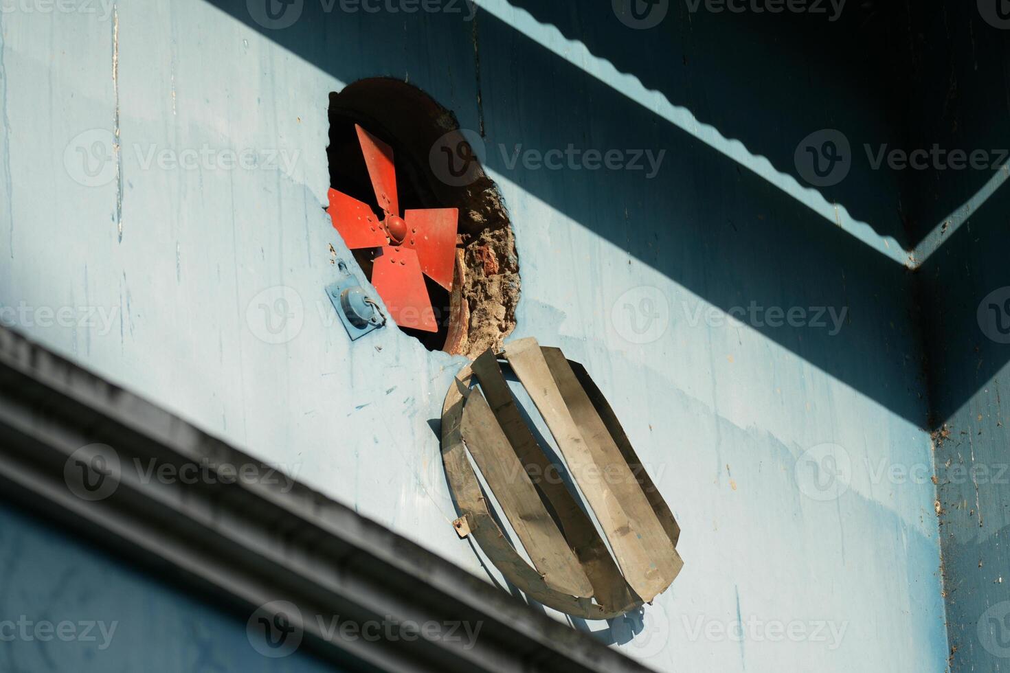 Damaged wall with exposed ventilation fan photo