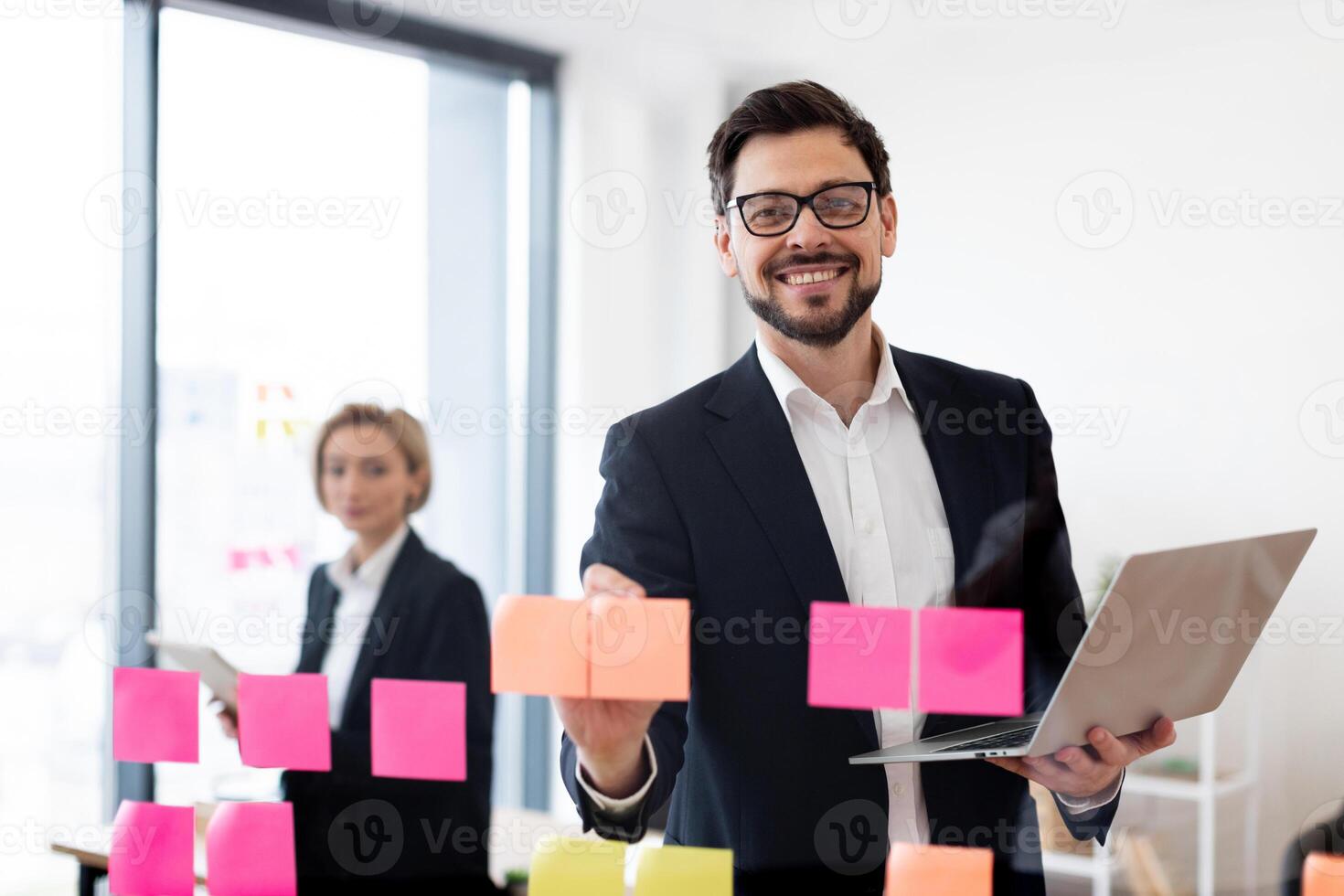 Young adult male and female business professionals collaborating with sticky notes and technology in professional workplace environment, showcasing teamwork, brainstorming photo