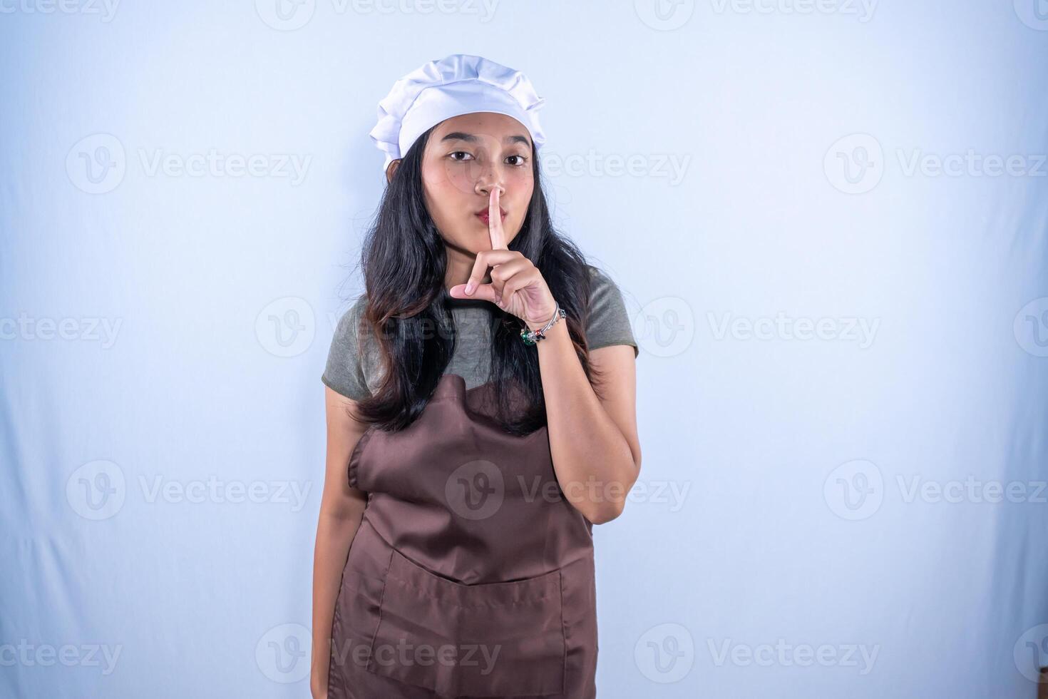 a woman in an apron is making a hush gesture photo