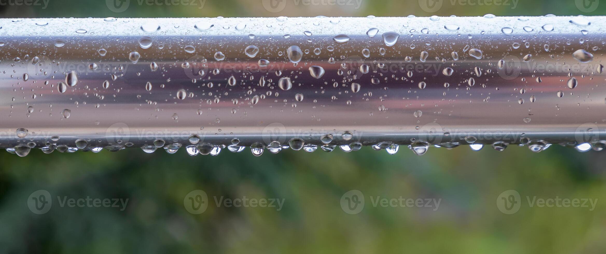 a close-up shot of a metal railing with water droplets clinging to it. photo