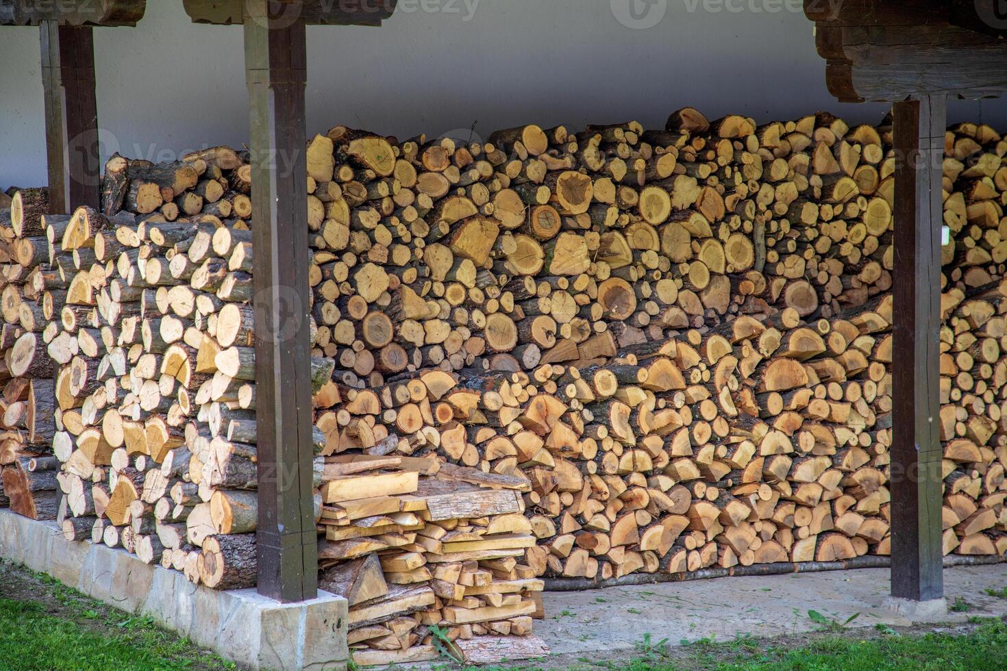 large stack of firewood neatly arranged under a covered area photo