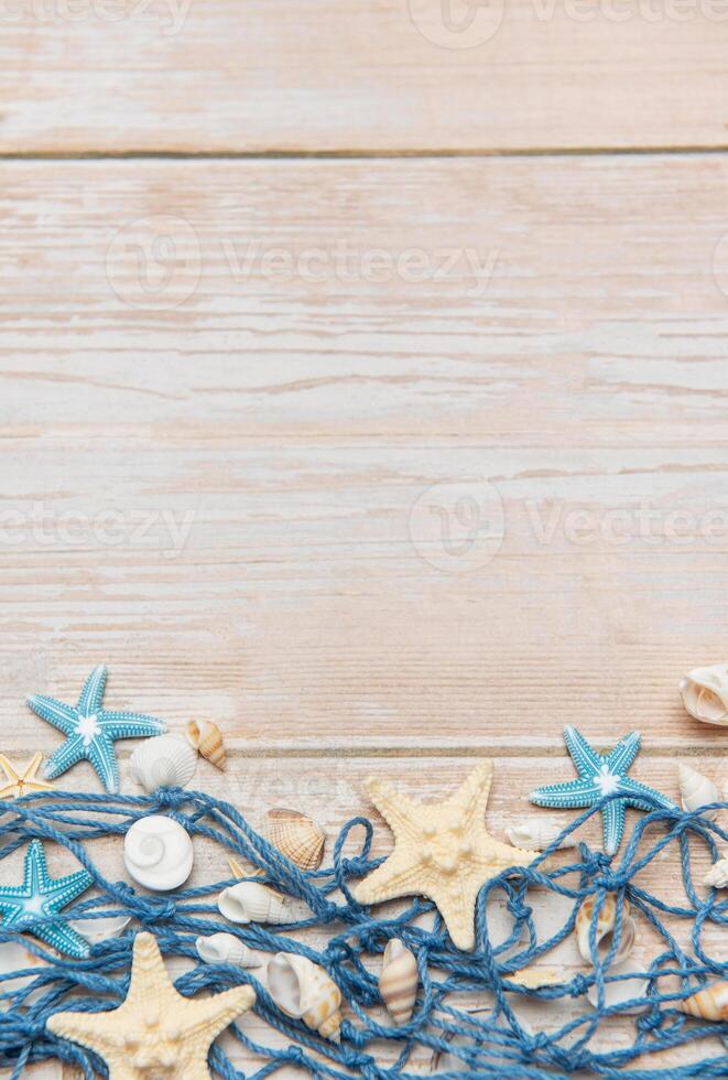 Fishing net with starfish and seashells creating summer holiday border on wooden planks photo