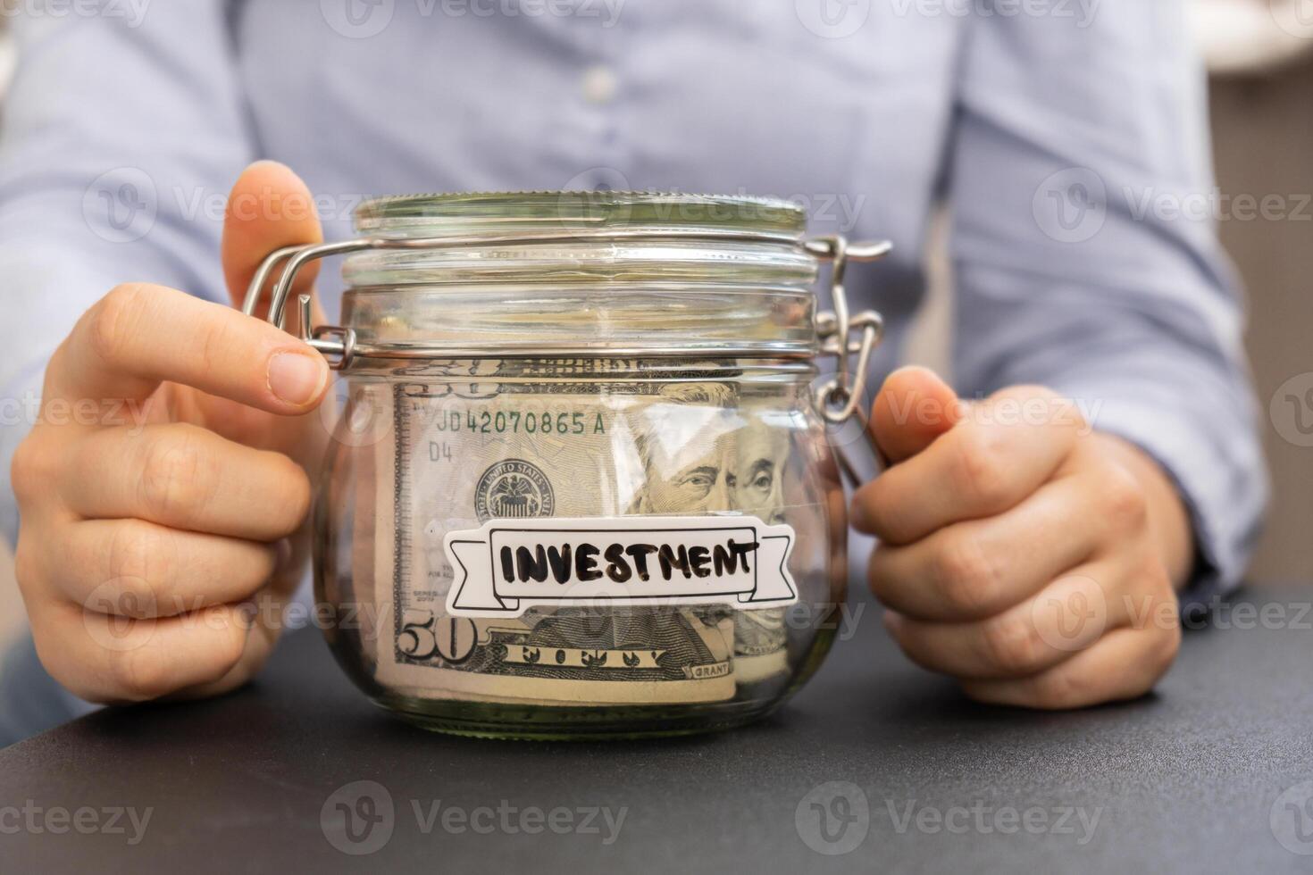 Unrecognizable woman holding Saving Money In Glass Jar filled with Dollars banknotes. INVESTMENT transcription in front of jar. Managing personal finances extra income for future insecurity background photo