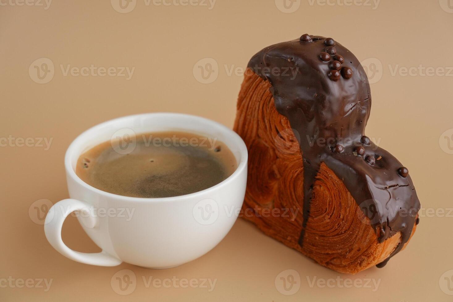 Coffee latte cappuccino drink beverage morning breakfast Heart shaped dark chocolate croissant on beige background with copy space. Puff pastry new trendy sweet dessert bakery. Creamy dough experiment photo