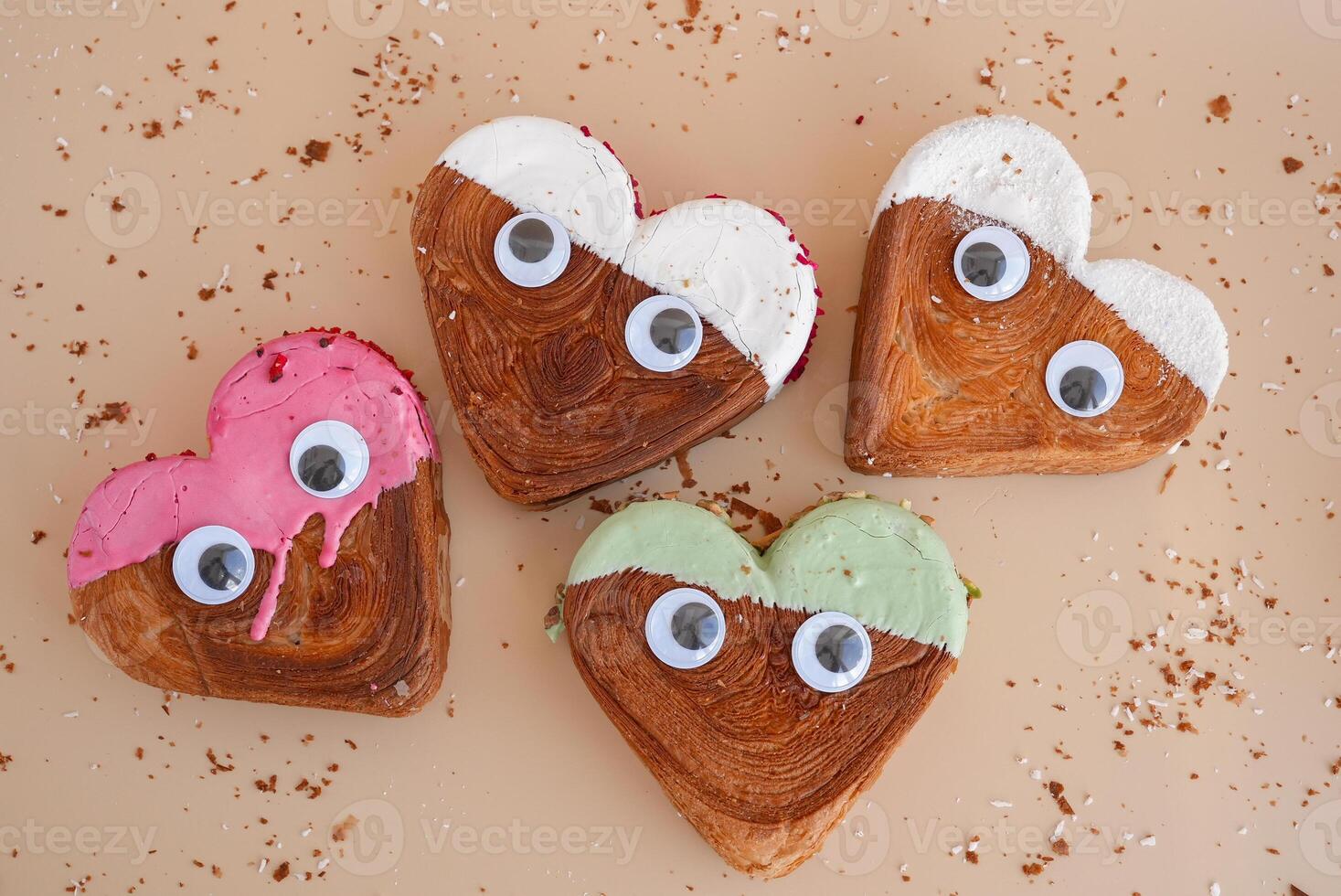 Funny eyes creative ides Valentine's Day flat lay top view Holiday celebration Heart shaped different variety flavor croissants on beige background with copy space. Puff pastry new trendy sweet dessert bakery. Creamy dough experiment photo
