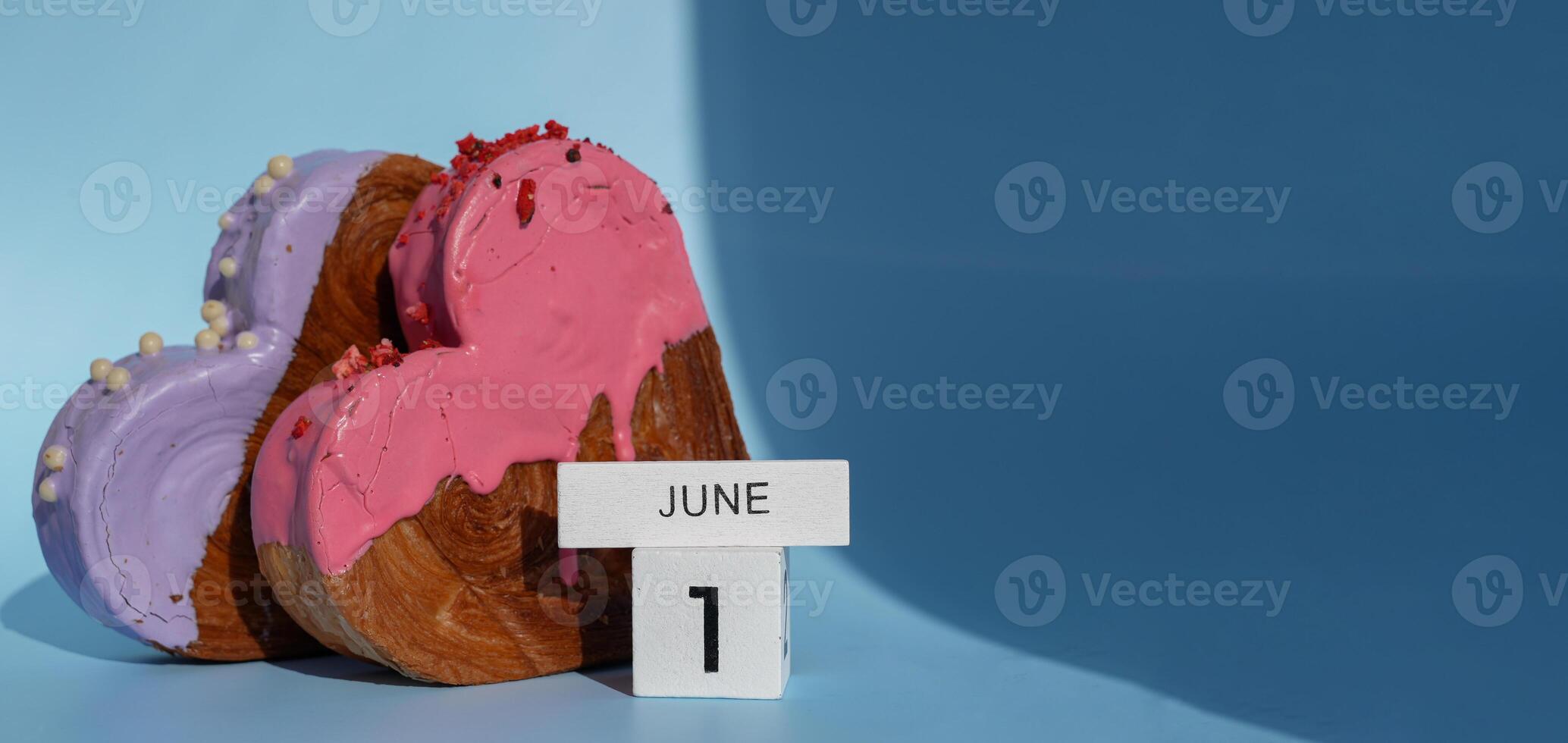 Calendar date 1 June International children's day greeting card Delicious fresh croissant topped with colorful flavor Ganache. Creation unique heart shape bakery. Puff pastry holiday love gift present idea. Copy space photo