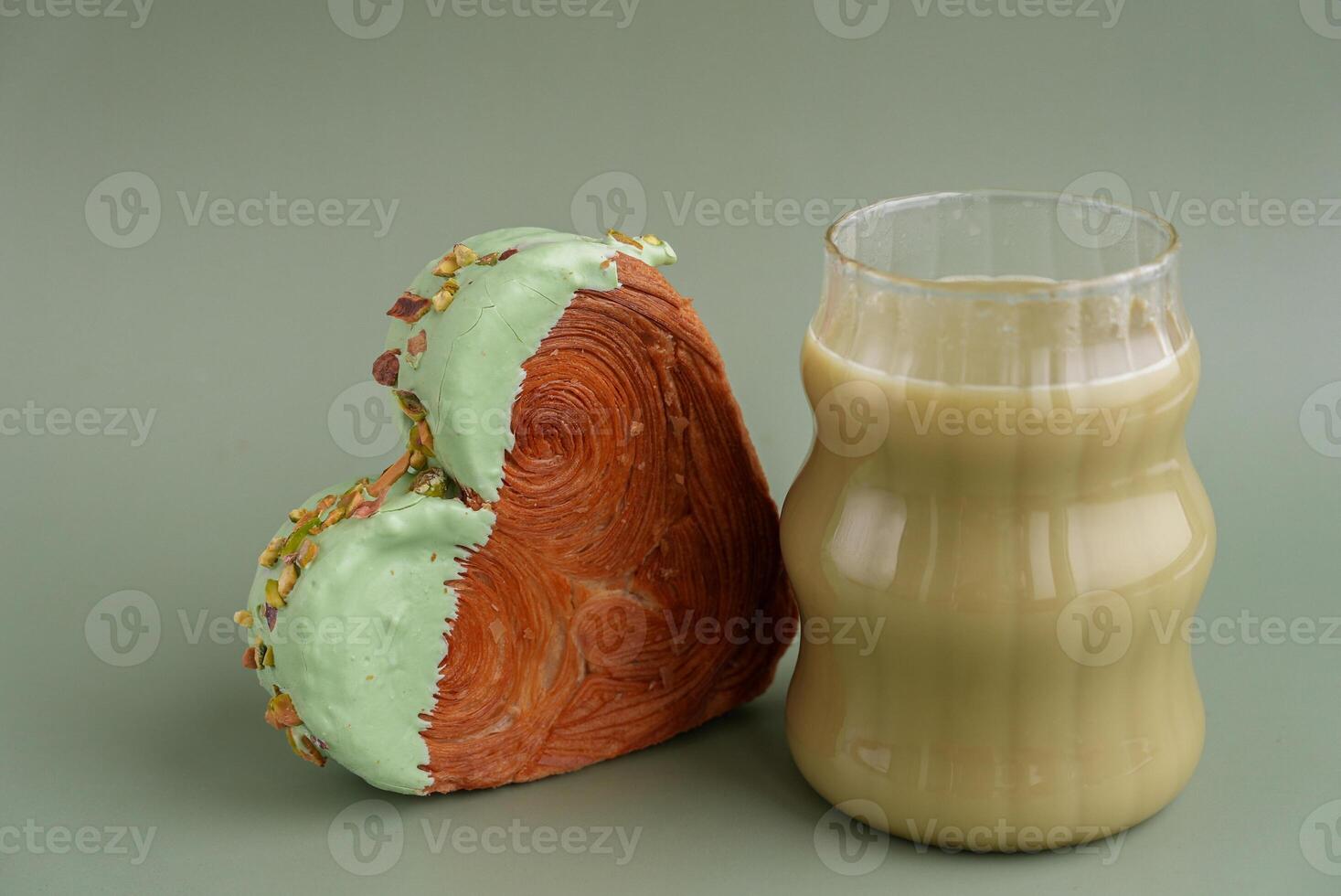 Green tea Matcha latte cappuccino beverage Morning breakfast gift idea Heart shaped pistachio croissant on green background with copy space. Puff pastry new trendy sweet dessert bakery. Creamy dough experiment photo