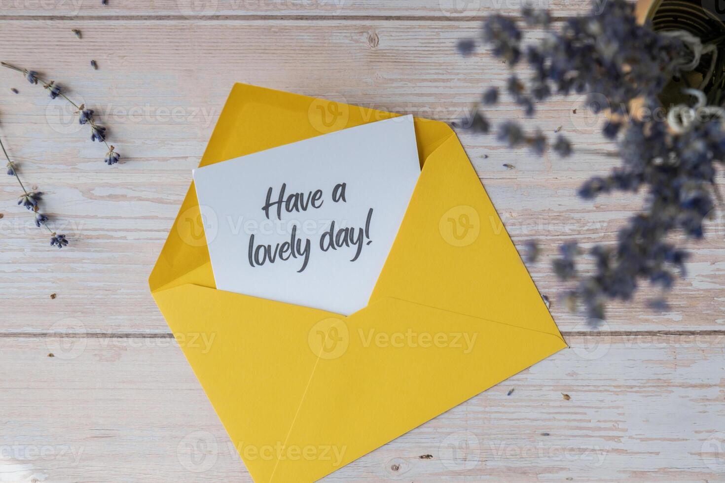 HAVE A LOVELY DAY text on supportive message paper note reminder from yellow envelope. Flat lay composition dry lavender flowers. Concept of inner happiness, slowing-down digital detox personal fulfillment. Top view photo