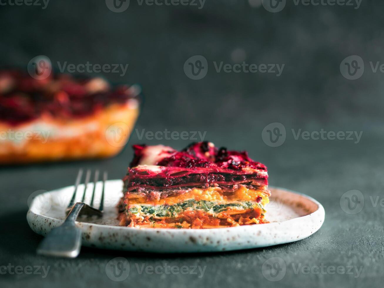 Vegetable Packed Rainbow lasagne on green background.Ideas and recipes for healthy vegetarian dinner or lunch.Lasagne with beetroot, pumpkin, mushrooms, ricotta, spinach, mozarella.Copy space for text photo