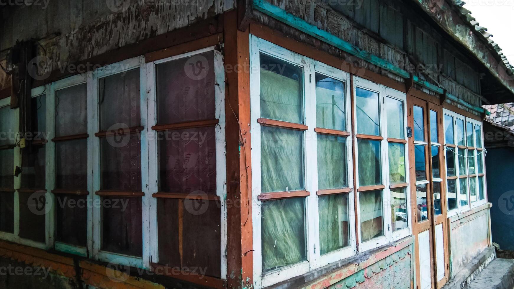 The corner of a simple Tengger tribe house is made of wood and is almost surrounded by glass windows. photo