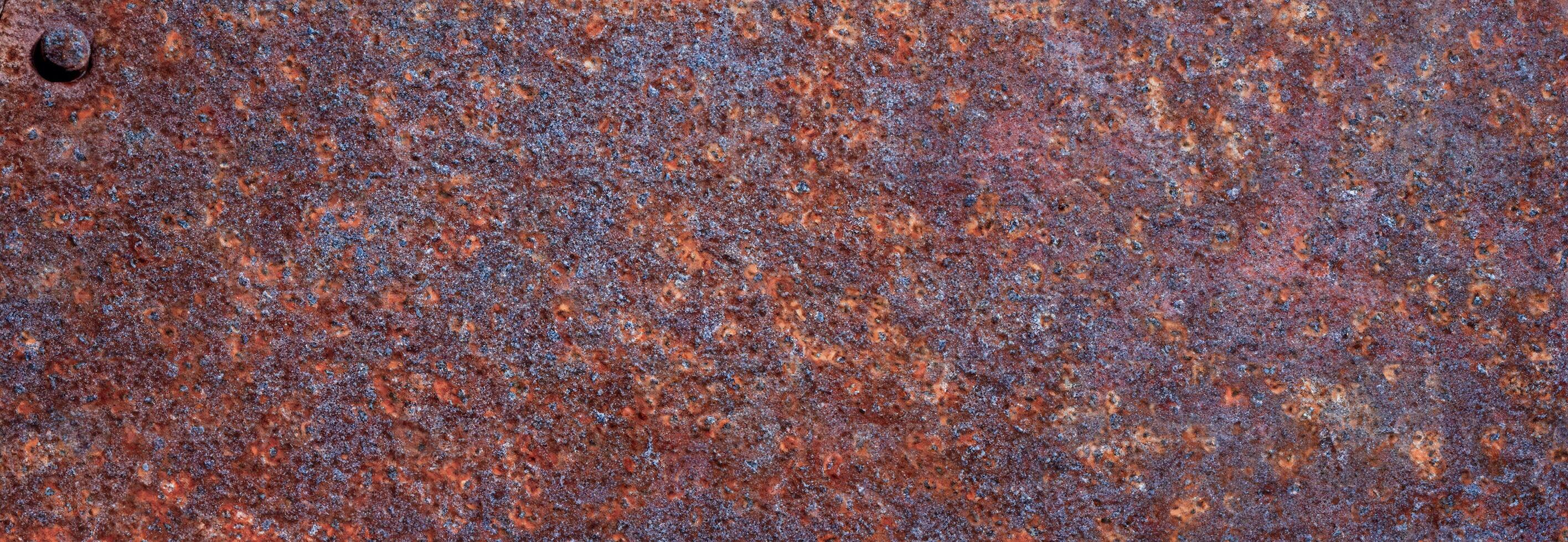Close-up of heavily rusted metal with corroded, gritty surface texture and reddish-brown coloration photo